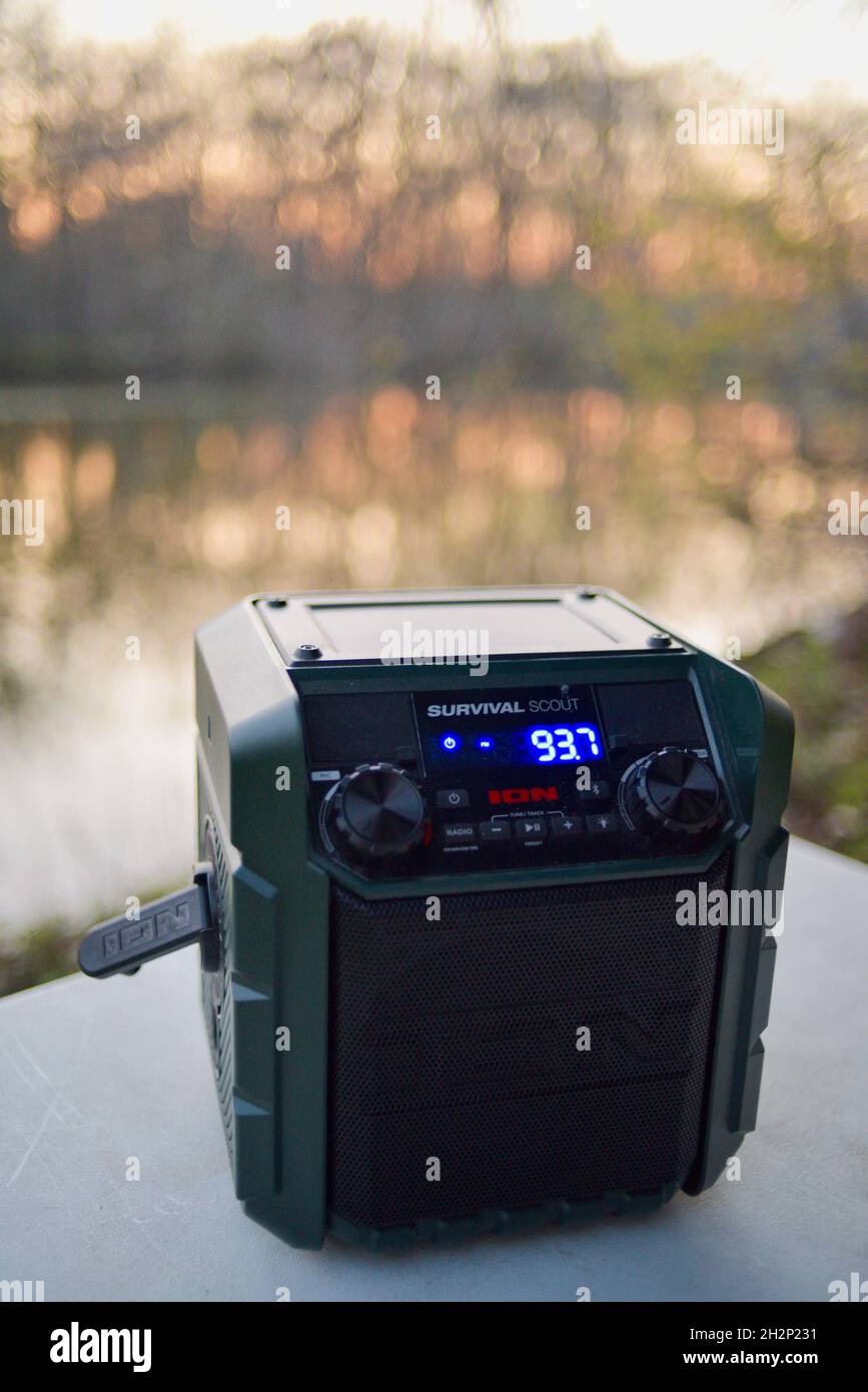 Ion Survival Scout portatile manovella a mano solare alimentato radio meteo di emergenza sul tavolo al campeggio nel bosco durante il tramonto, Woodford, Wisconsin, Stati Uniti Foto Stock