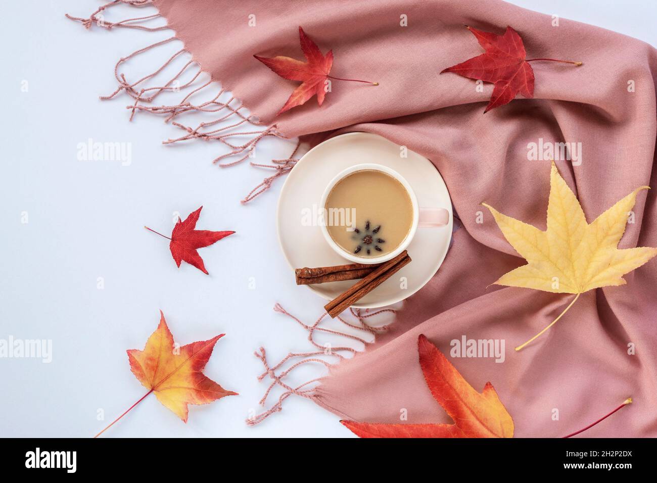 Caffè caldo con anice stellato e cannella in una tazza e foglie d'autunno su sfondo rosa sciarpa di cashmere. Vista dall'alto, piatto. Concetto di caduta. Foto Stock