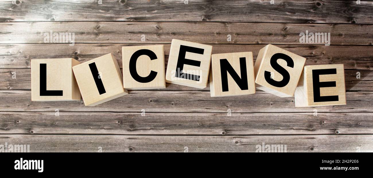 PAROLA DI LICENZA composta da blocchi di costruzione su sfondo di legno Foto Stock