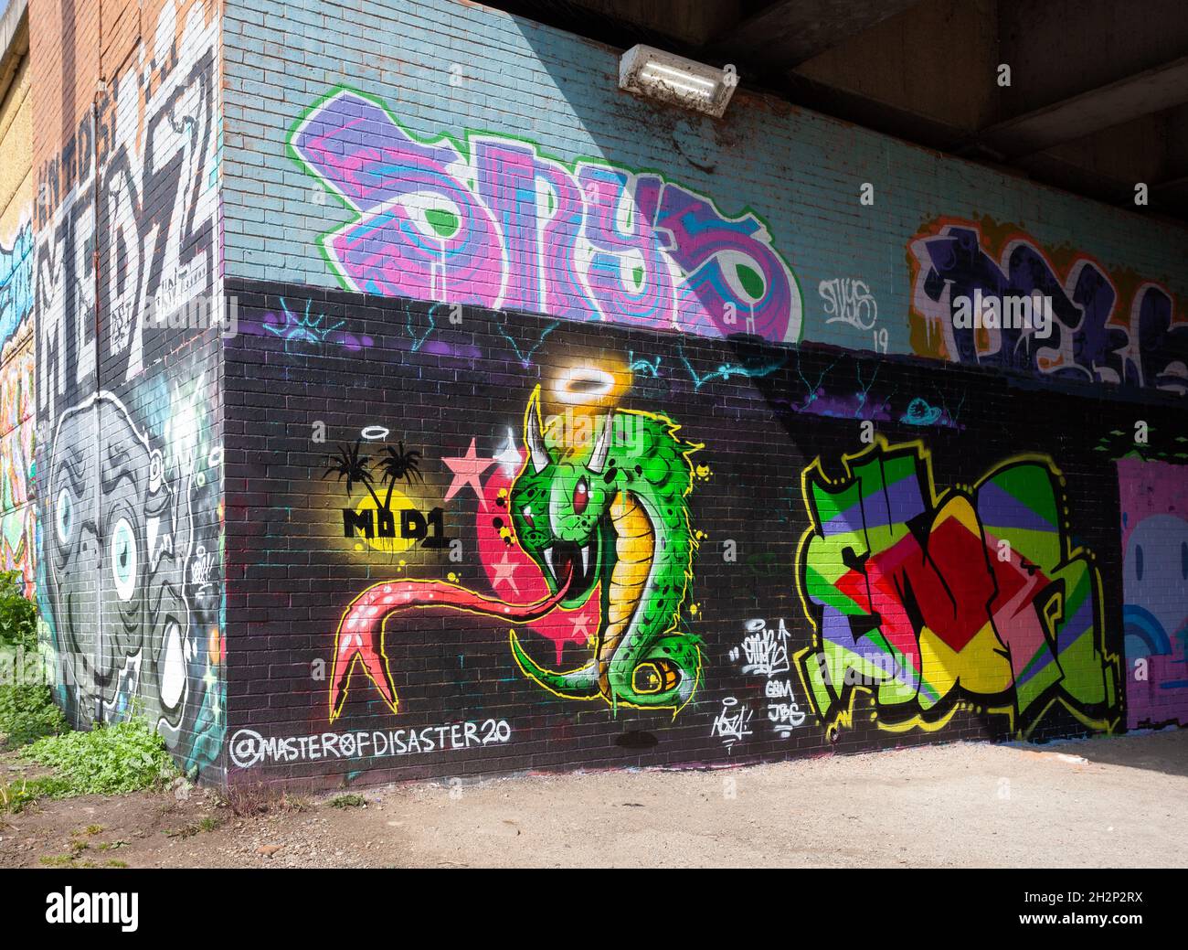 Graffiti colorati / Street art accanto al fiume Aire sentiero lungo il fiume a Leeds, West Yorkshire Foto Stock