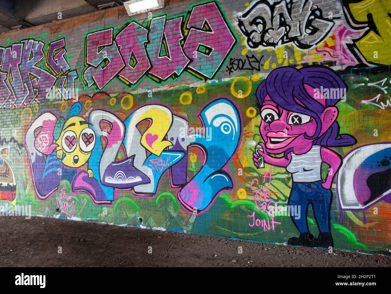 Graffiti colorati / Street art accanto al fiume Aire sentiero lungo il fiume a Leeds, West Yorkshire Foto Stock