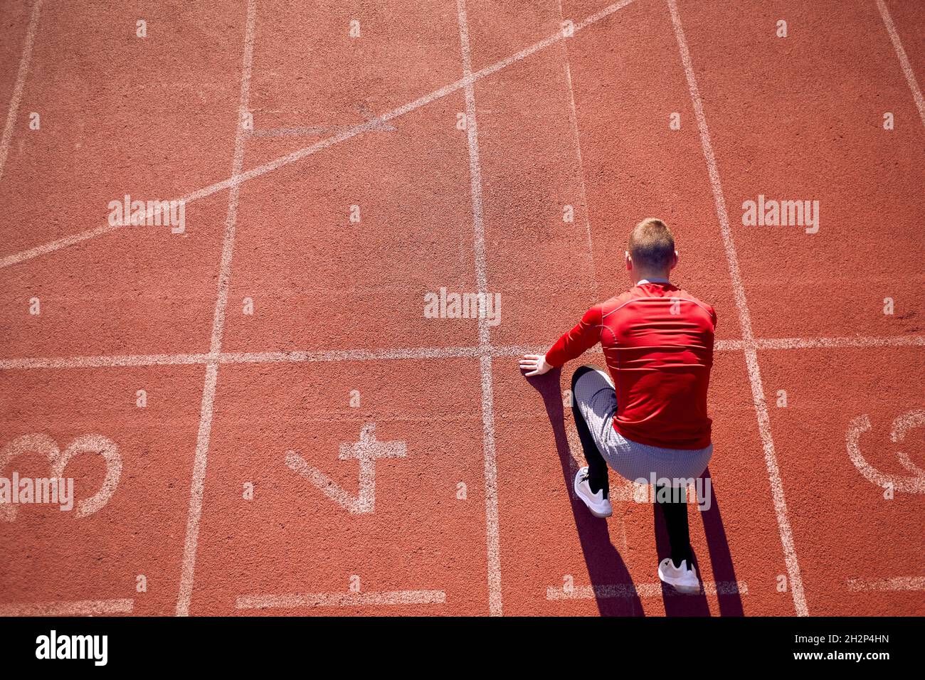 immagine dall'alto del giovane atleta maschile adulto in posizione di partenza bassa sul tracciato atletico. posizione linea di partenza. spazio di copia Foto Stock