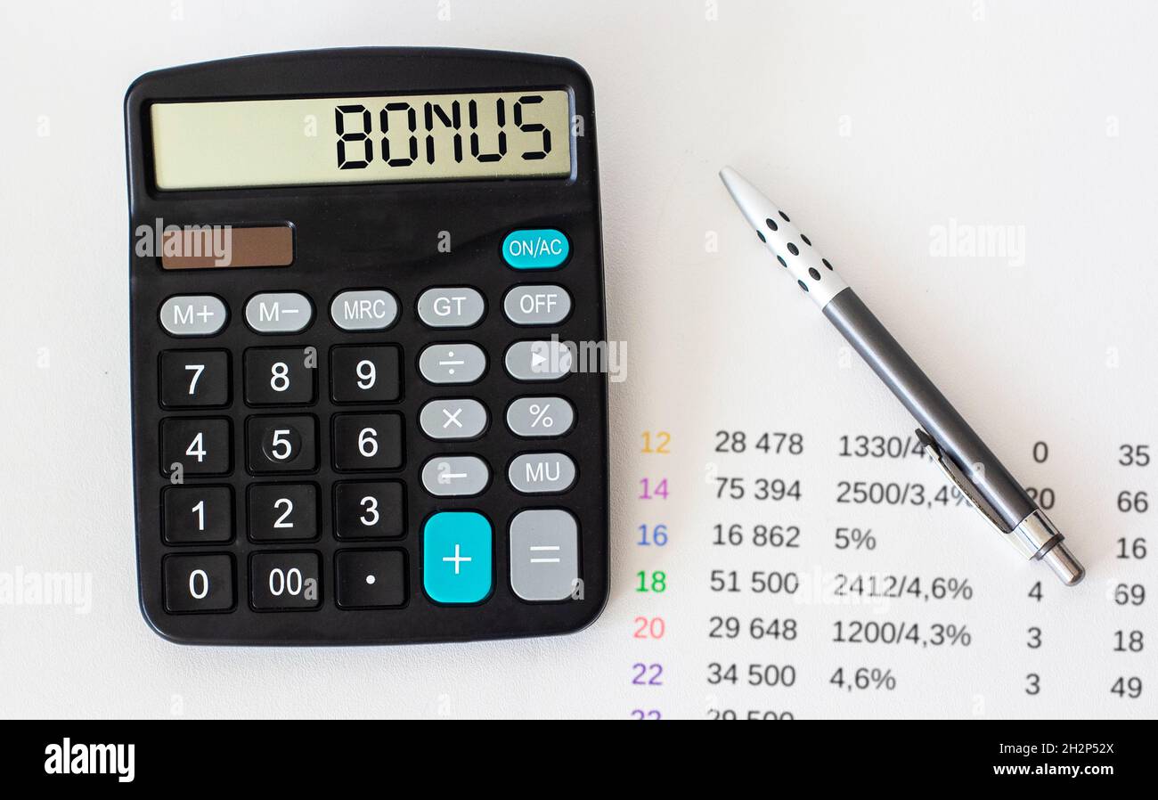 La calcolatrice visualizza la parola BONUS. Su uno sfondo bianco con numeri e penna Foto Stock