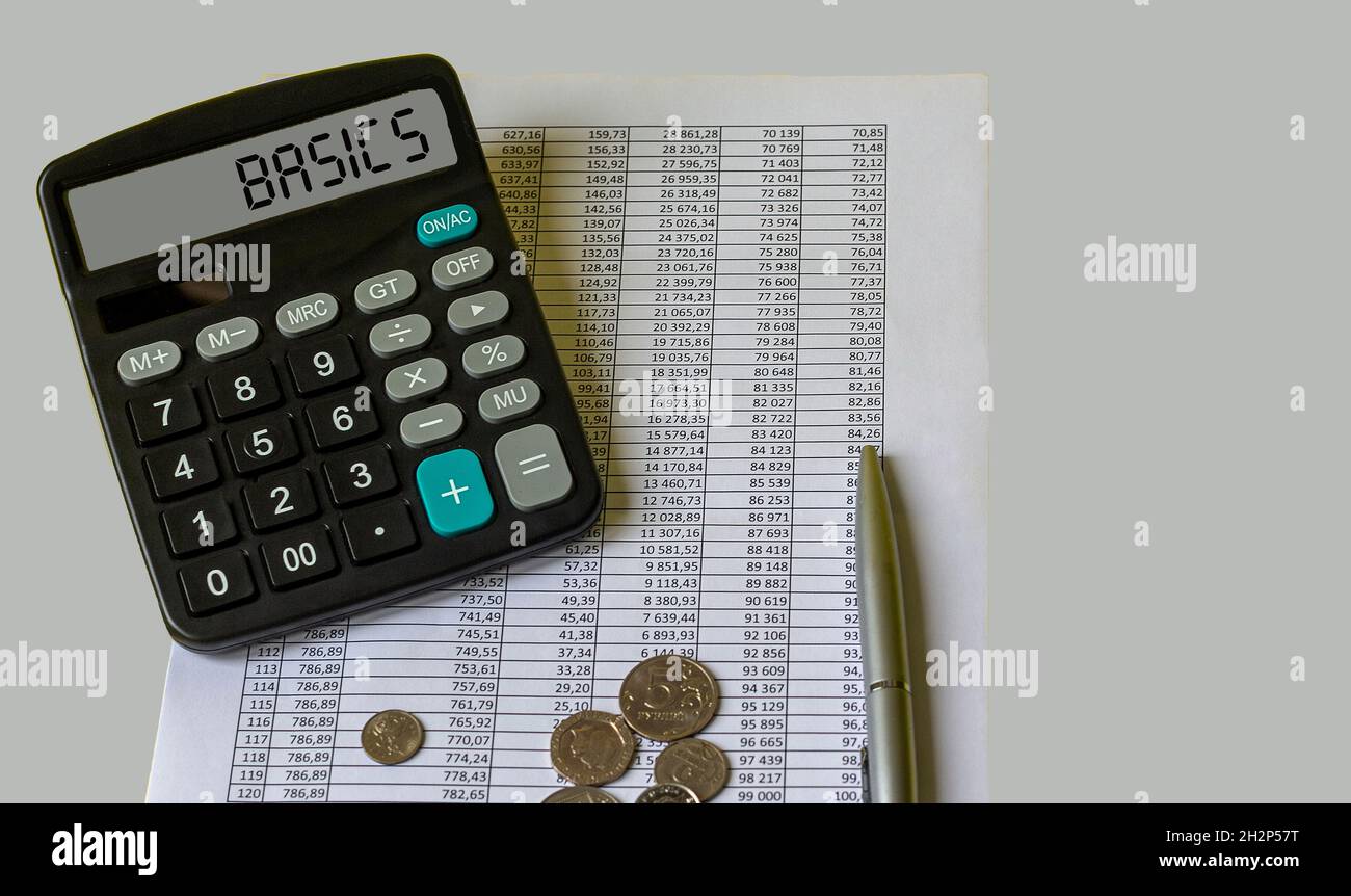 Parola DI BASE su foglio giallo su tabella con penna, calcolatrice e grafico. Concetto di business e finanza. Foto Stock