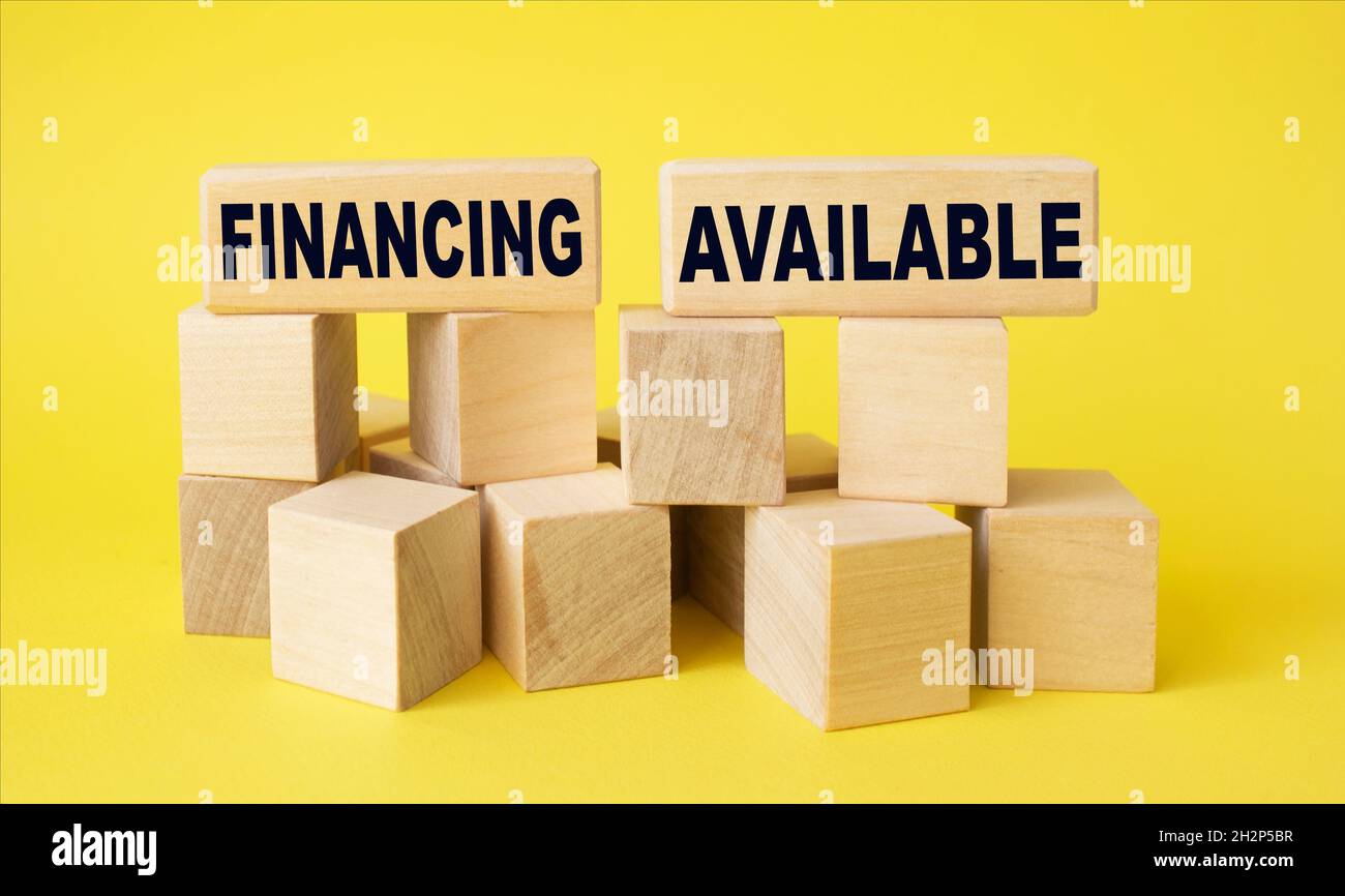 Concetto di business su cubi di legno. È disponibile il finanziamento tramite testo. Sfondo giallo Foto Stock
