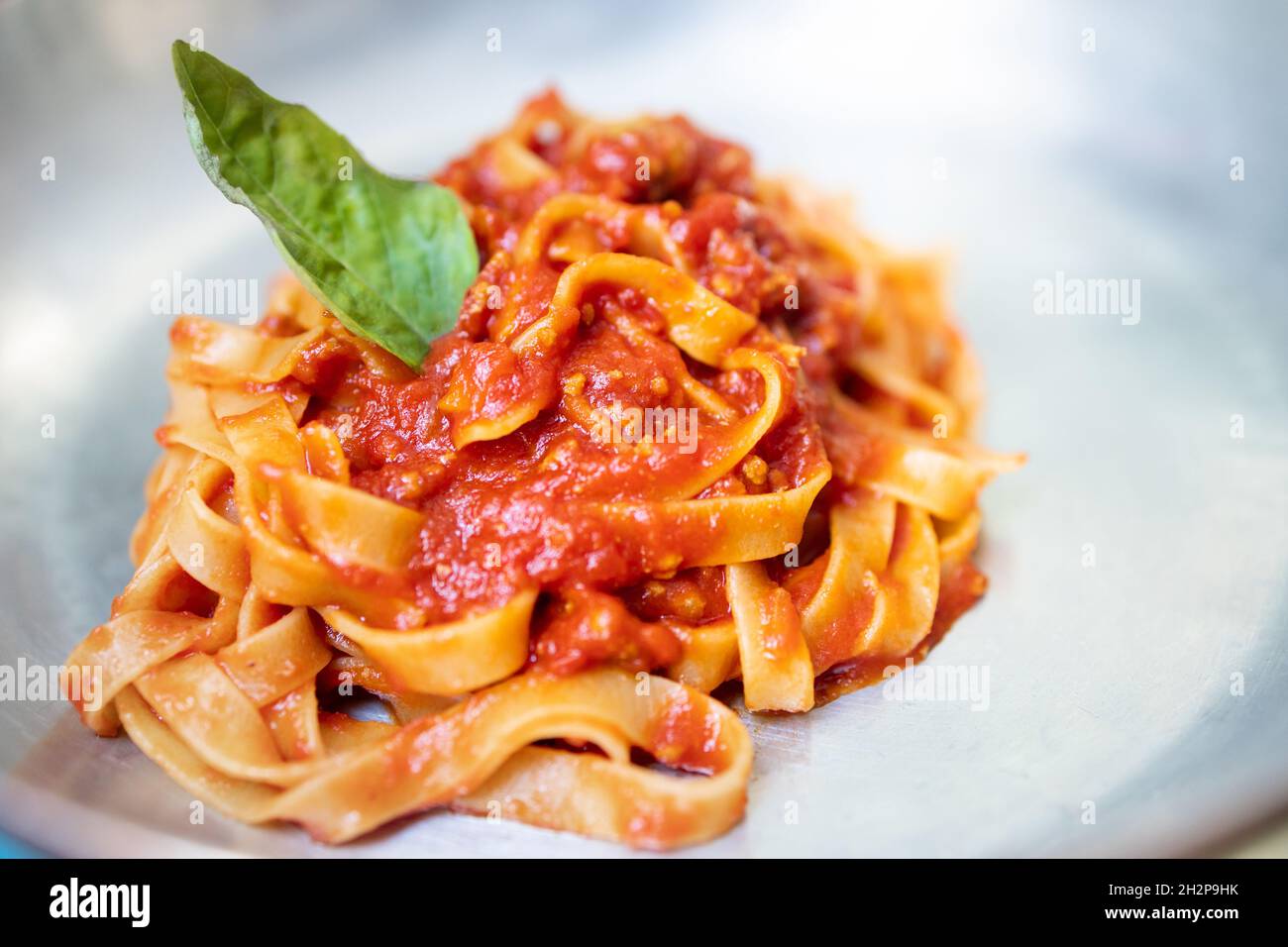 Tagliatelle al sugo di bolognese con foglia di basilico. Foto Stock