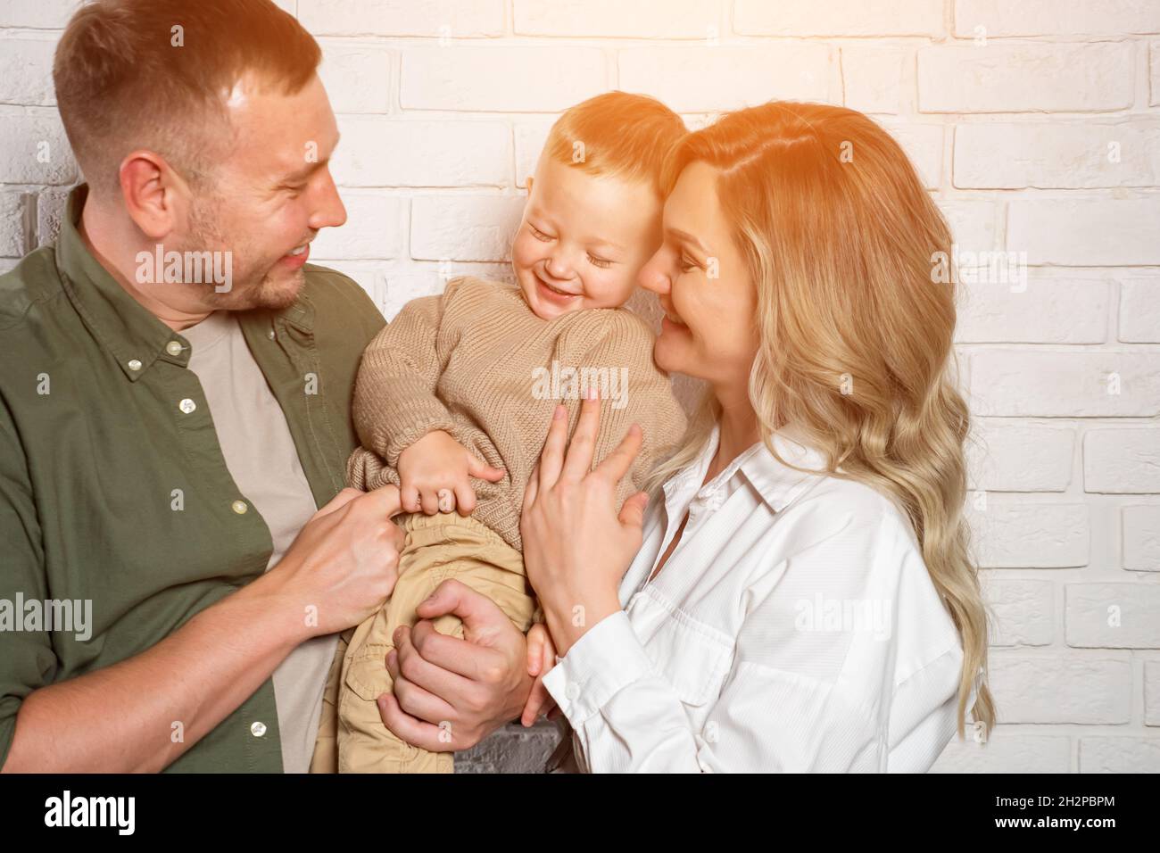 La famiglia felice posa per la foto abbracciante e sorridente dolcemente Foto Stock