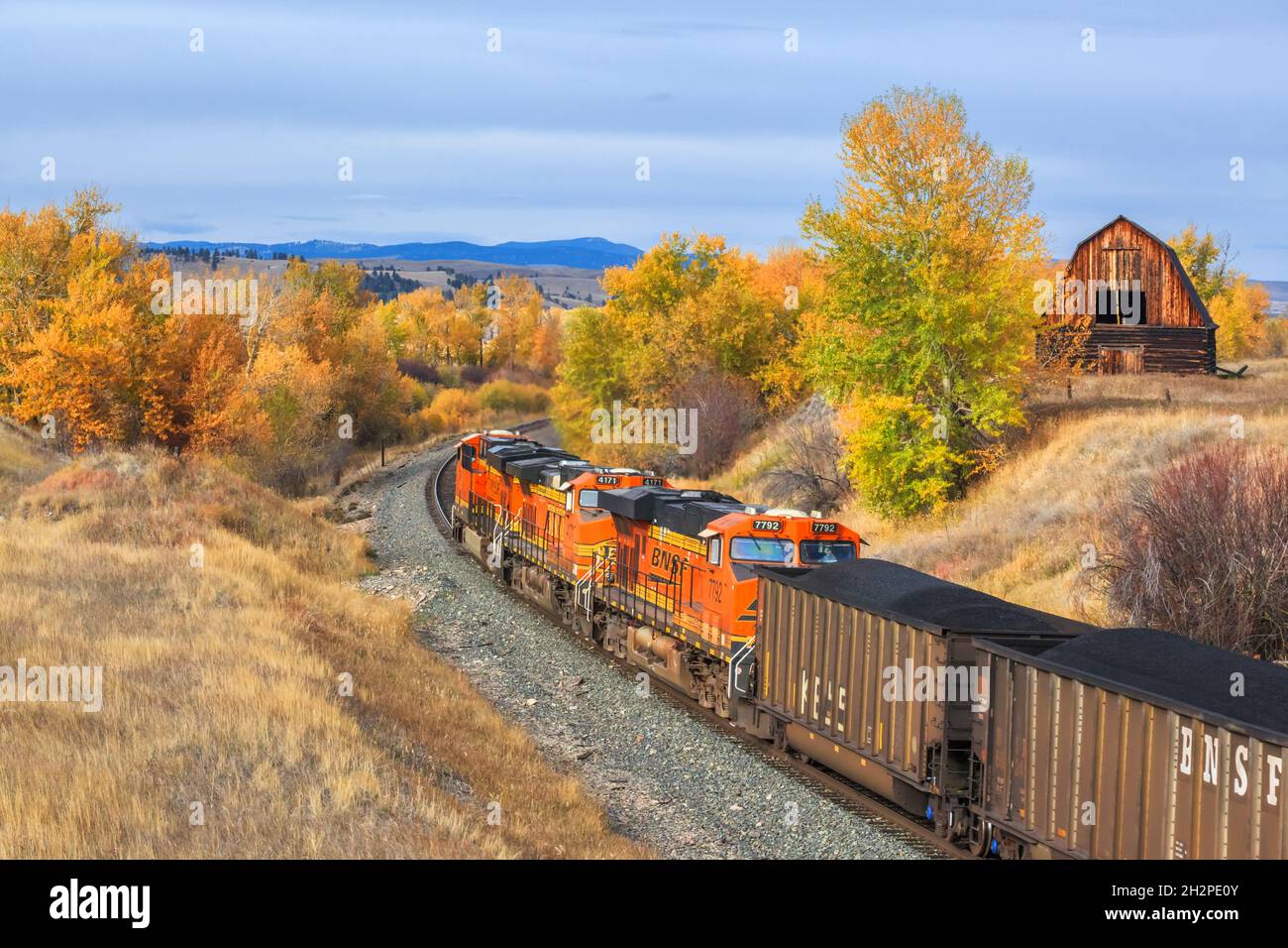 treno che passa da un vecchio fienile in autunno a jens, montana Foto Stock