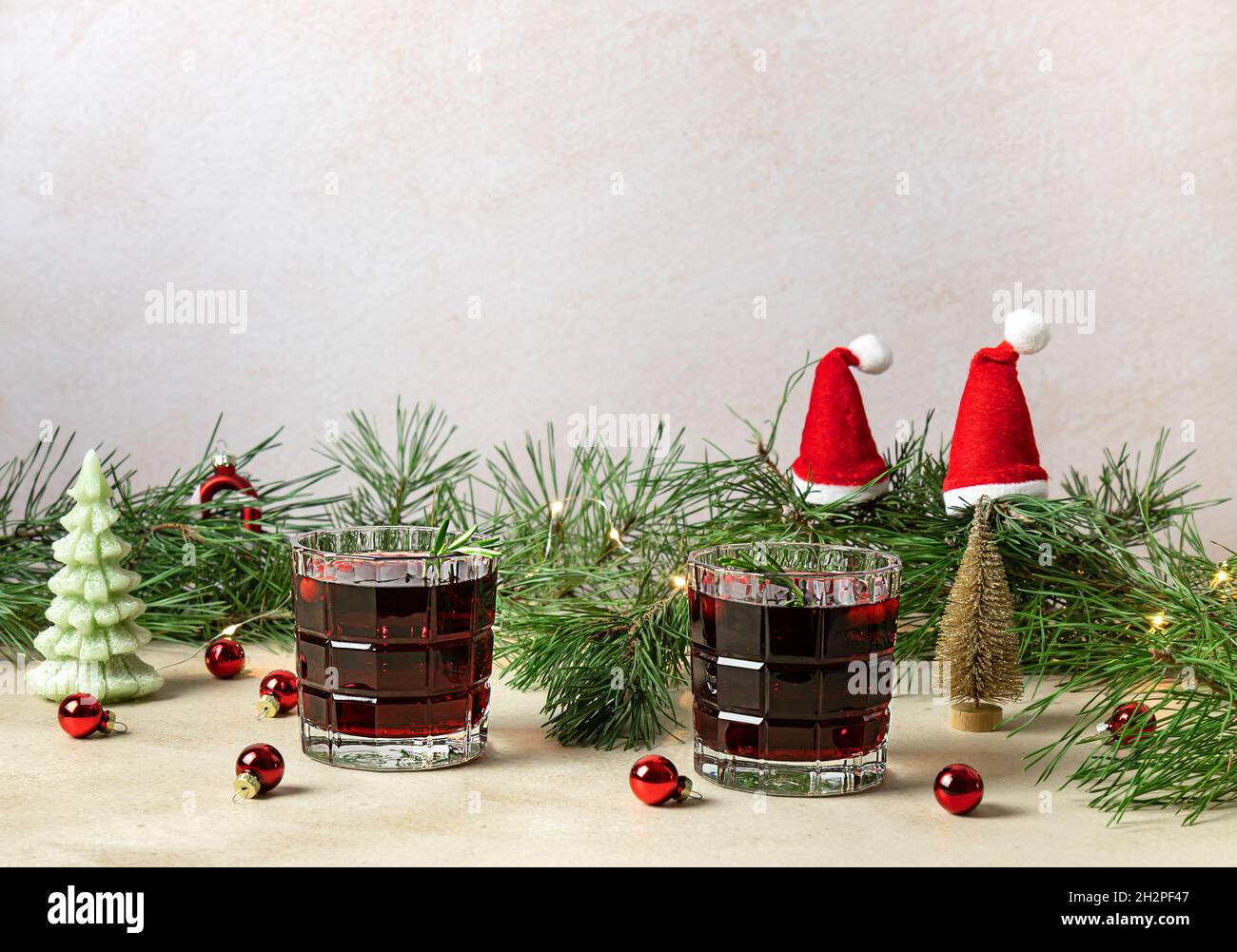Cocktail natalizio al mirtillo e rosmarino con ghiaccio sullo sfondo decorato della vacanza. VIN brulé alcolico o non alcolico. Foto Stock