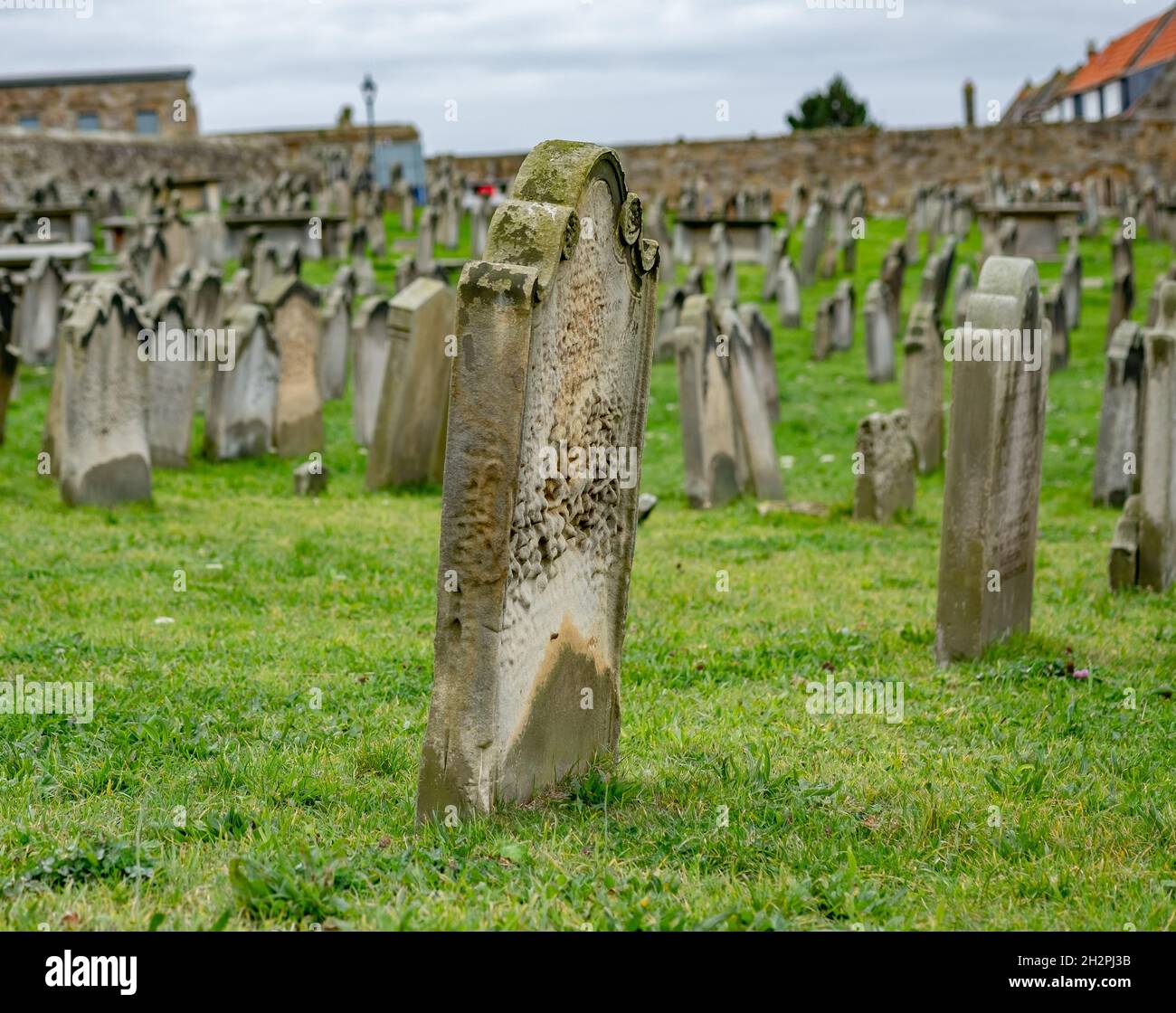Whitby, Yorkshire, Regno Unito – Ottobre 20 2021. Focalizzazione ravvicinata e selettiva su un'antica lapide, risalente all'Ottocento, in un cimitero con le rovine di A. Foto Stock