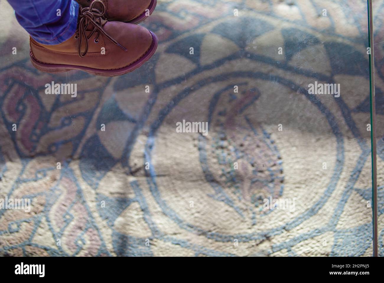 I piedi del bambino sopra il pavimento di vetro dei mosaici della casa dell'anfiteatro, Merida. Estremadura, Spagna Foto Stock