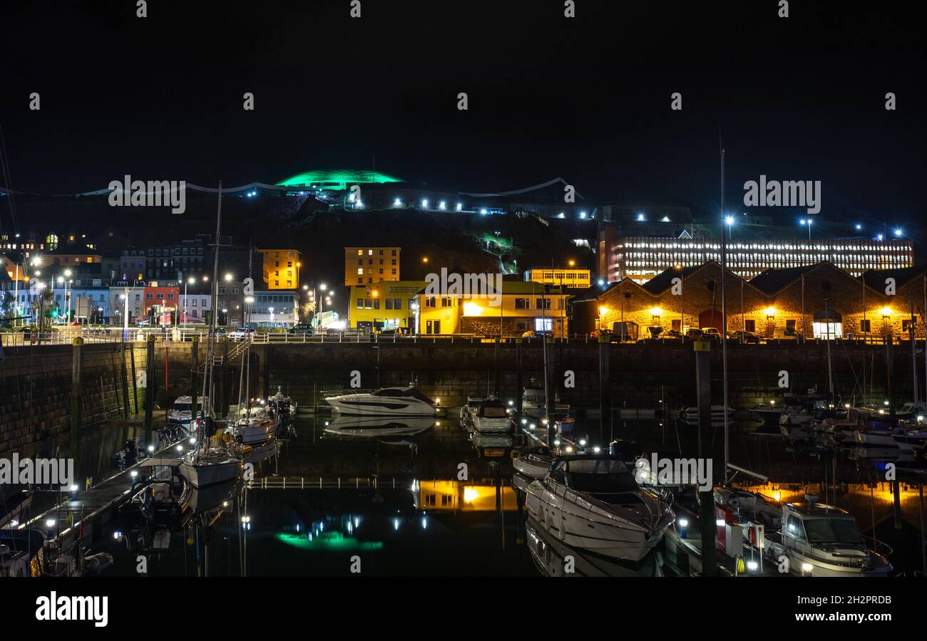 Marina con yacht e luci notturne della città sullo sfondo, Saint Helier, bailiwick di Jersey, Isole del canale Foto Stock