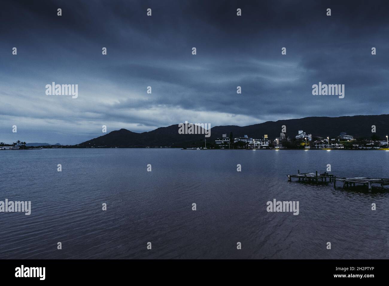 Notte oceano e montagne scure. Città di pescatori di notte. Foto Stock