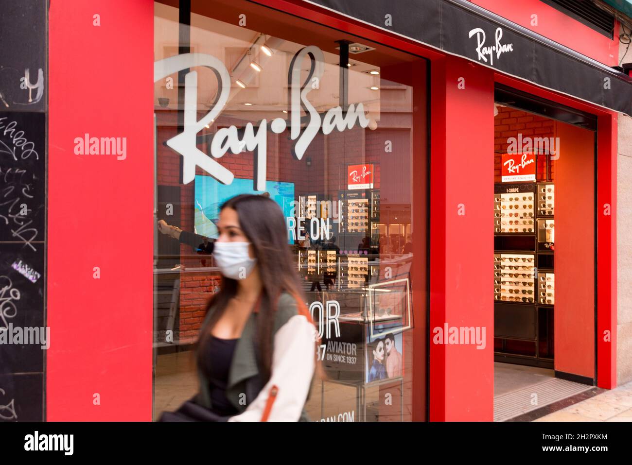 Una donna passa di fronte al negozio di occhiali da sole Ray Ban a Valencia. Foto Stock