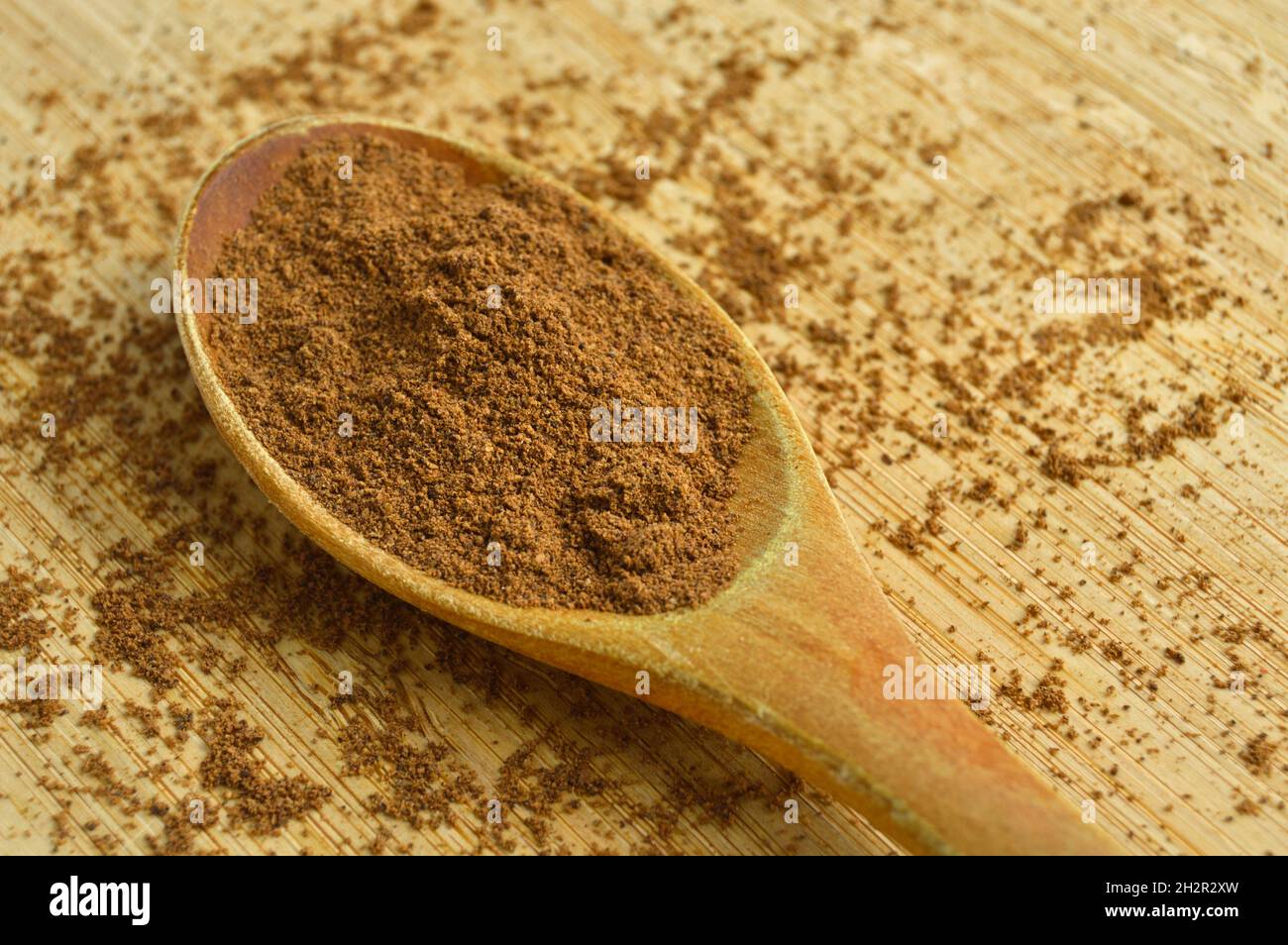 Spezie in polvere allspice in cucchiaio di legno, bambù su tagliere Foto Stock