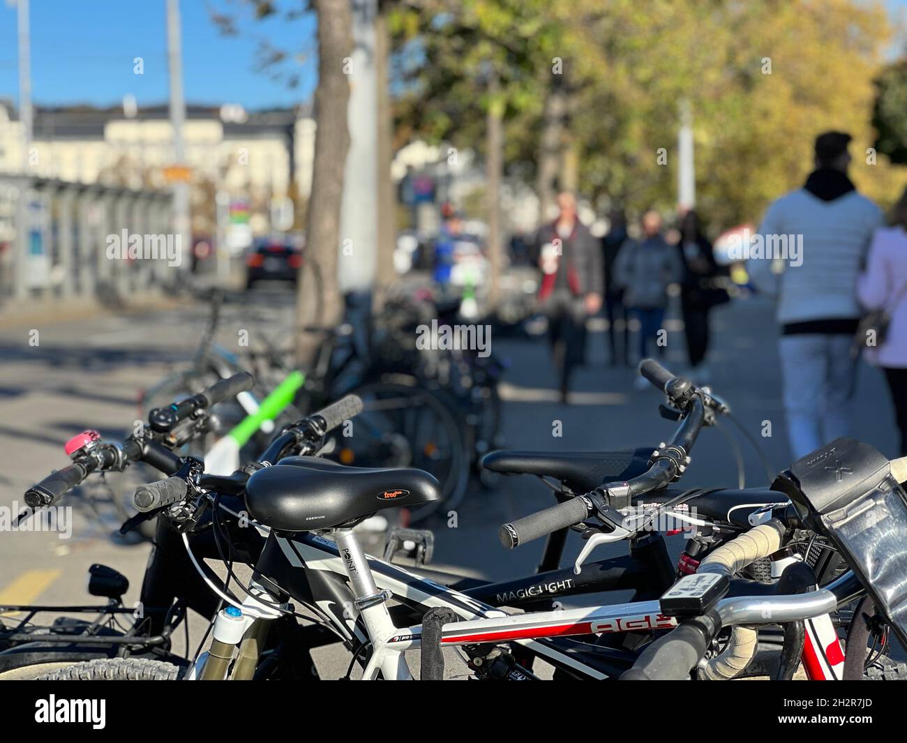 Biciclette parcheggiate nel centro della città. Sullo sfondo ci sono persone che fanno una passeggiata nel centro della città in una chiara giornata autunnale nel mese di ottobre. Foto Stock