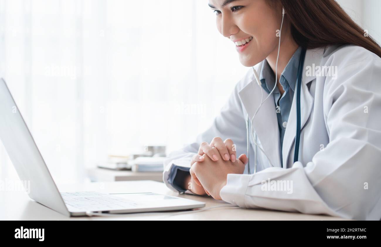 Il medico asiatico della donna è in linea che visita con un paziente sopra L'applicazione Internet e l'ascolto dei sintomi e spiega come trattare il d iniziale Foto Stock