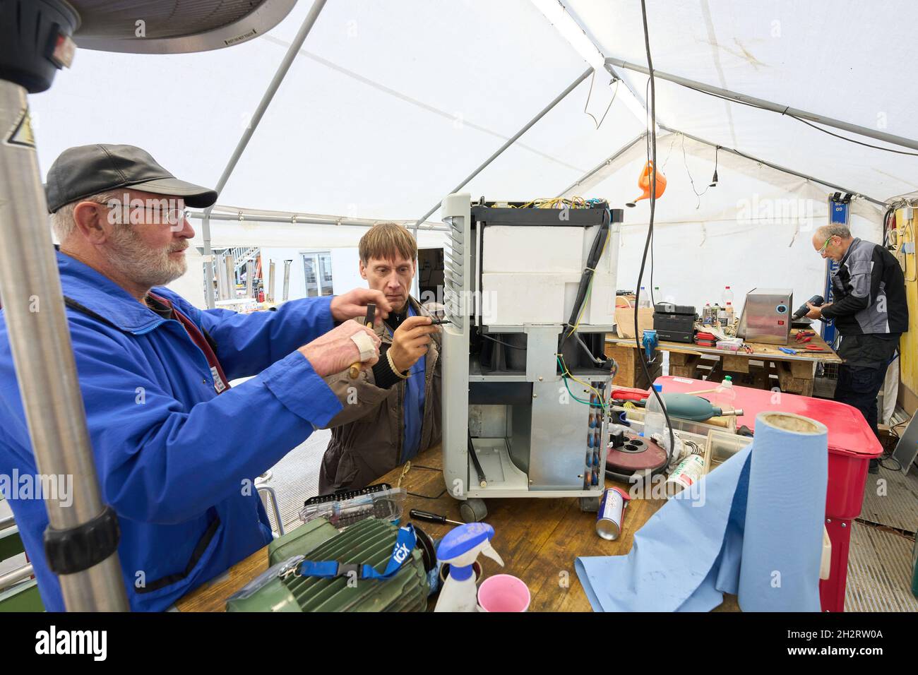 Walporzheim, Germania. 21 ottobre 2021. I due 'Elektroseelsorger' Thomas (l) e Iwer riparano un essiccatore da cantiere nella tenda dell'officina. L'associazione "Elektroseelsorge(r)", finanziata con donazioni, è composta da circa 220 elettricisti, tecnici delle telecomunicazioni e altri volontari provenienti da tutta la Germania. Si fangosi e una volta soddensi elettrodomestici come trapani, cacciaviti cordless, macchine da cucina e riscaldatori che funzionano di nuovo. (A dpa: ''Elektroseelsorge(r)' nella Valle dell'Ahr: 'Festival of Lights' as a Sign of Hope') Credit: Thomas Frey/dpa/Alamy Live News Foto Stock
