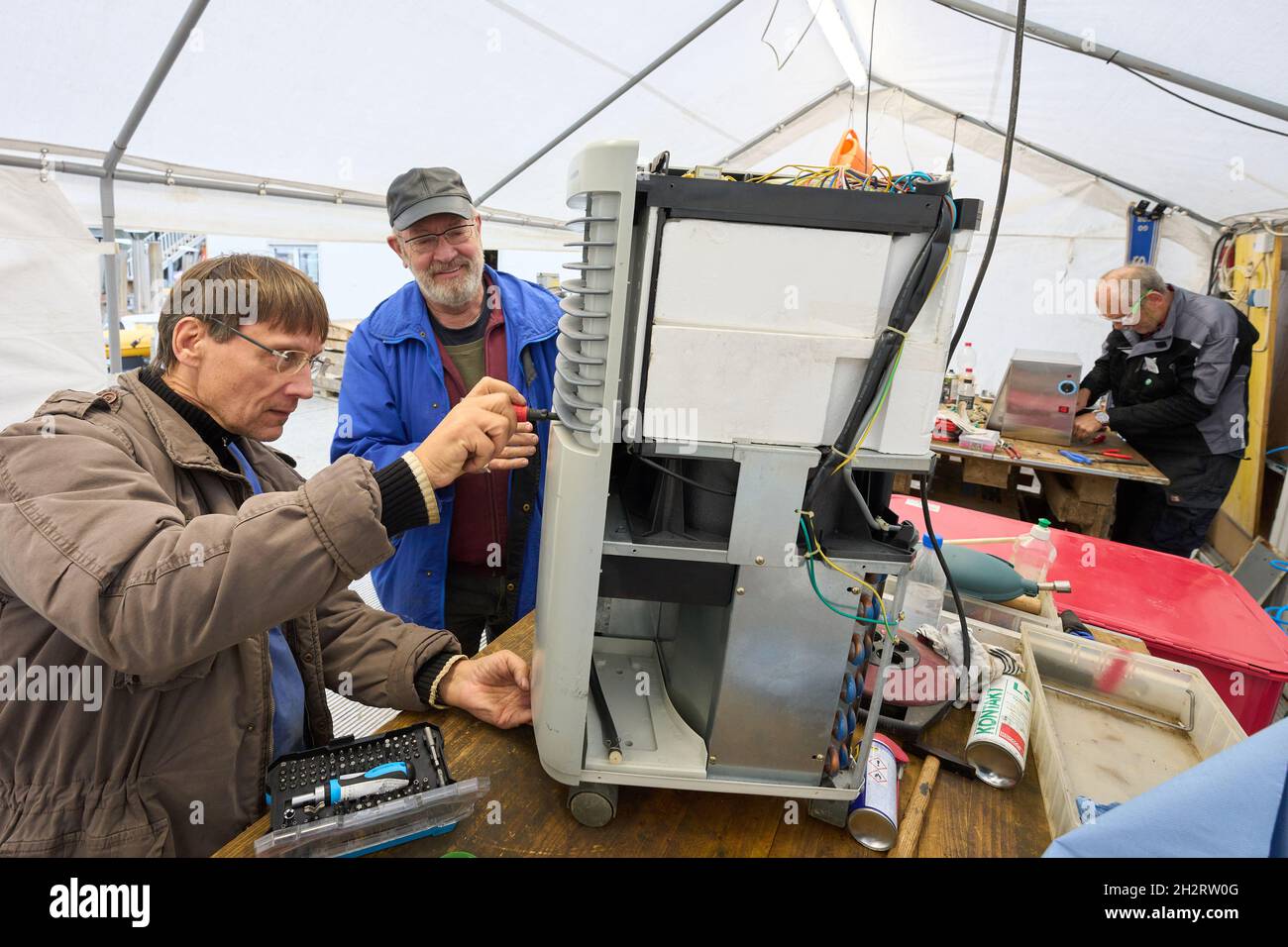 Walporzheim, Germania. 21 ottobre 2021. I due 'Elektroseelsorger' Thomas (l) e Iwer riparano un essiccatore da cantiere nella tenda dell'officina. L'associazione "Elektroseelsorge(r)", finanziata con donazioni, è composta da circa 220 elettricisti, tecnici delle telecomunicazioni e altri volontari provenienti da tutta la Germania. Si fangosi e una volta soddensi elettrodomestici come trapani, cacciaviti cordless, macchine da cucina e riscaldatori che funzionano di nuovo. (A dpa: ''Elektroseelsorge(r)' nella Valle dell'Ahr: 'Festival of Lights' as a Sign of Hope') Credit: Thomas Frey/dpa/Alamy Live News Foto Stock