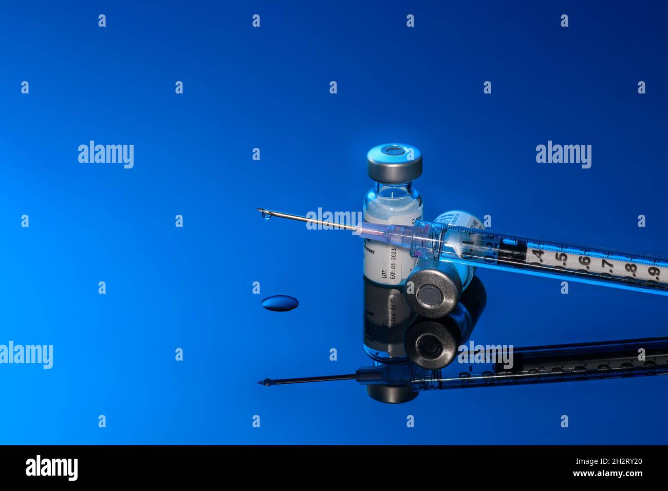 Siringa con flaconcini e ago su sfondo blu Foto Stock