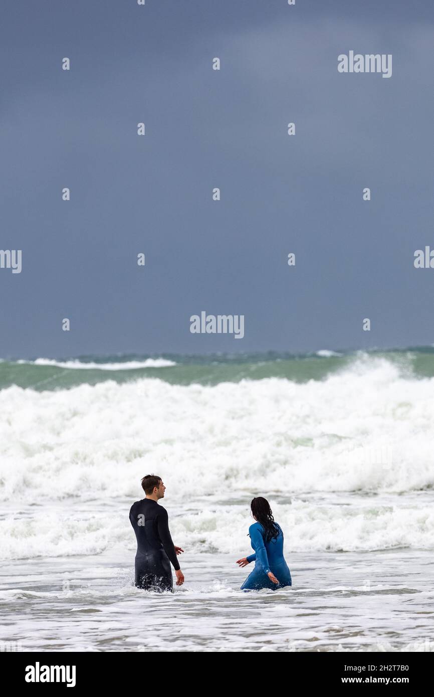 Nuotatori in tute bagnate che fanno surf sulla spiaggia di Polzeath North Cornwall, Regno Unito Foto Stock