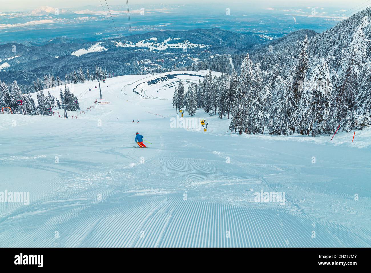 Sciatore sulla spettacolare pista da sci. Funivia e ghiacciata vista lago dalla pista da sci, Poiana Brasov, Carpazi, Romania, Europa Foto Stock