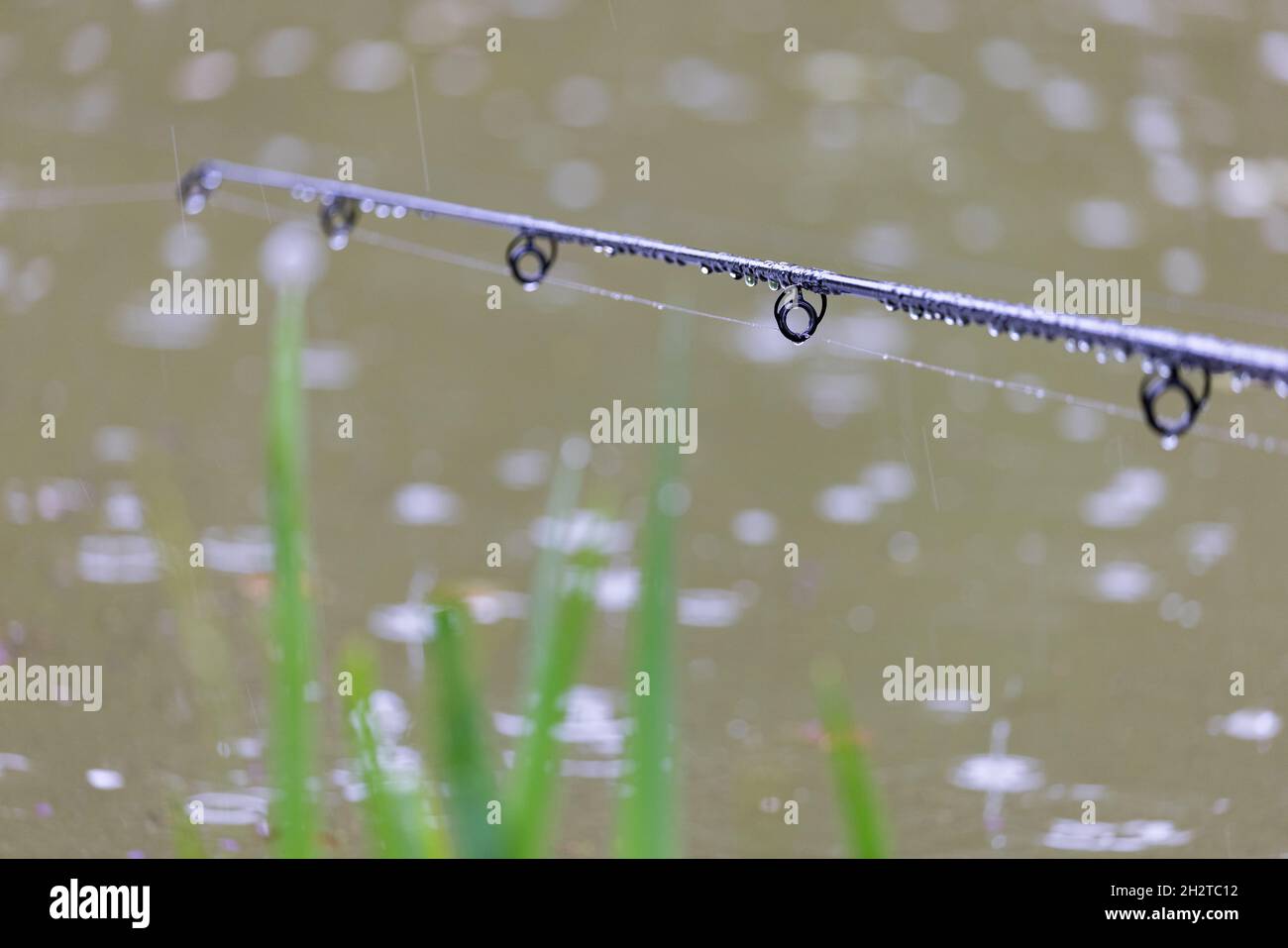 pioggia e canna da pesca contro il lago in ascesa Foto Stock