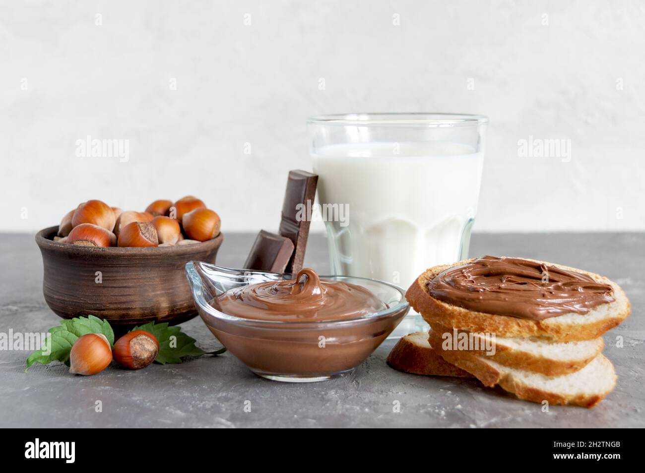 Crema di noci al cioccolato con latte e toast croccanti per colazione. Composizione in primo piano sul tavolo. Foto Stock