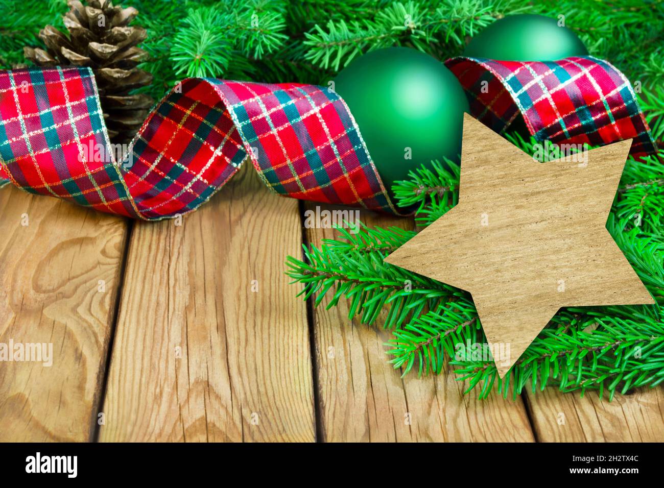 Decorazioni natalizie di colore rosso verde con rami di abete e stella su sfondo in legno Foto Stock