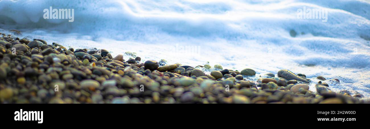 Sfondi marini. Schiuma di mare bianca e ciottoli scuri. Contrasti. Foto Stock