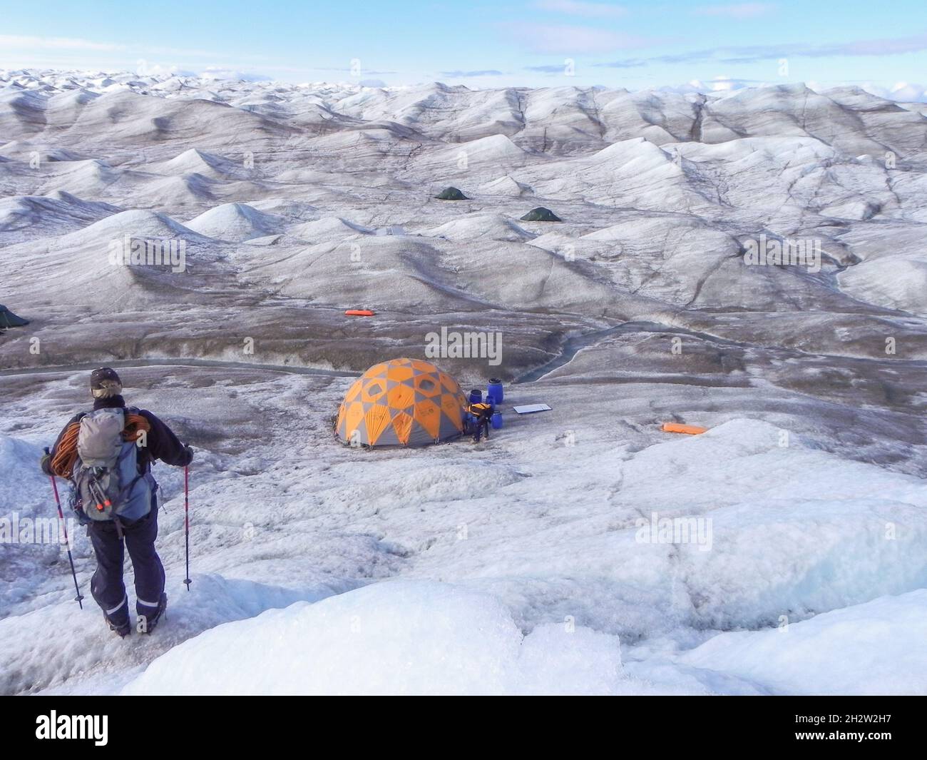 Tenda e zaino in spalla sulla vastità della calotta glaciale della Groenlandia Foto Stock