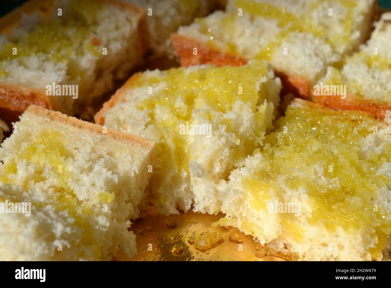 Pezzi di pane italiano fresco ingrassati con olio d'oliva posti sul vassoio d'oro sotto il sole luminoso. Primo piano. Foto Stock