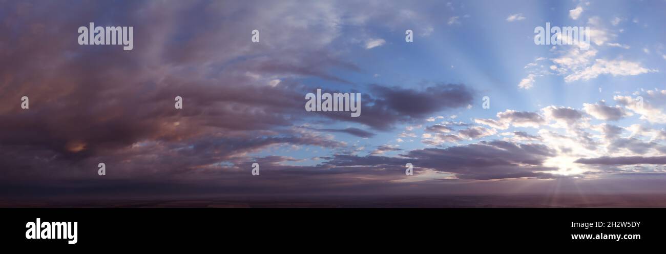 Panorama di cielo drammatico all'alba o al tramonto. Astrazione di nuvole sfocate e il sole che si infrange attraverso le nuvole Foto Stock