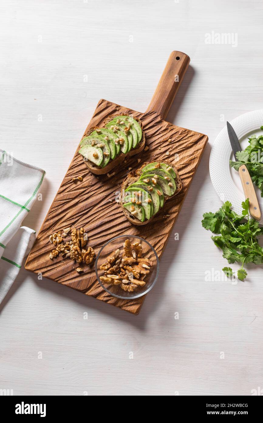 Sandwich all'avocado su pane di segale scuro preparato con avocado fresco affettato dall'alto. Concetto di colazione. Vista dall'alto. Foto Stock