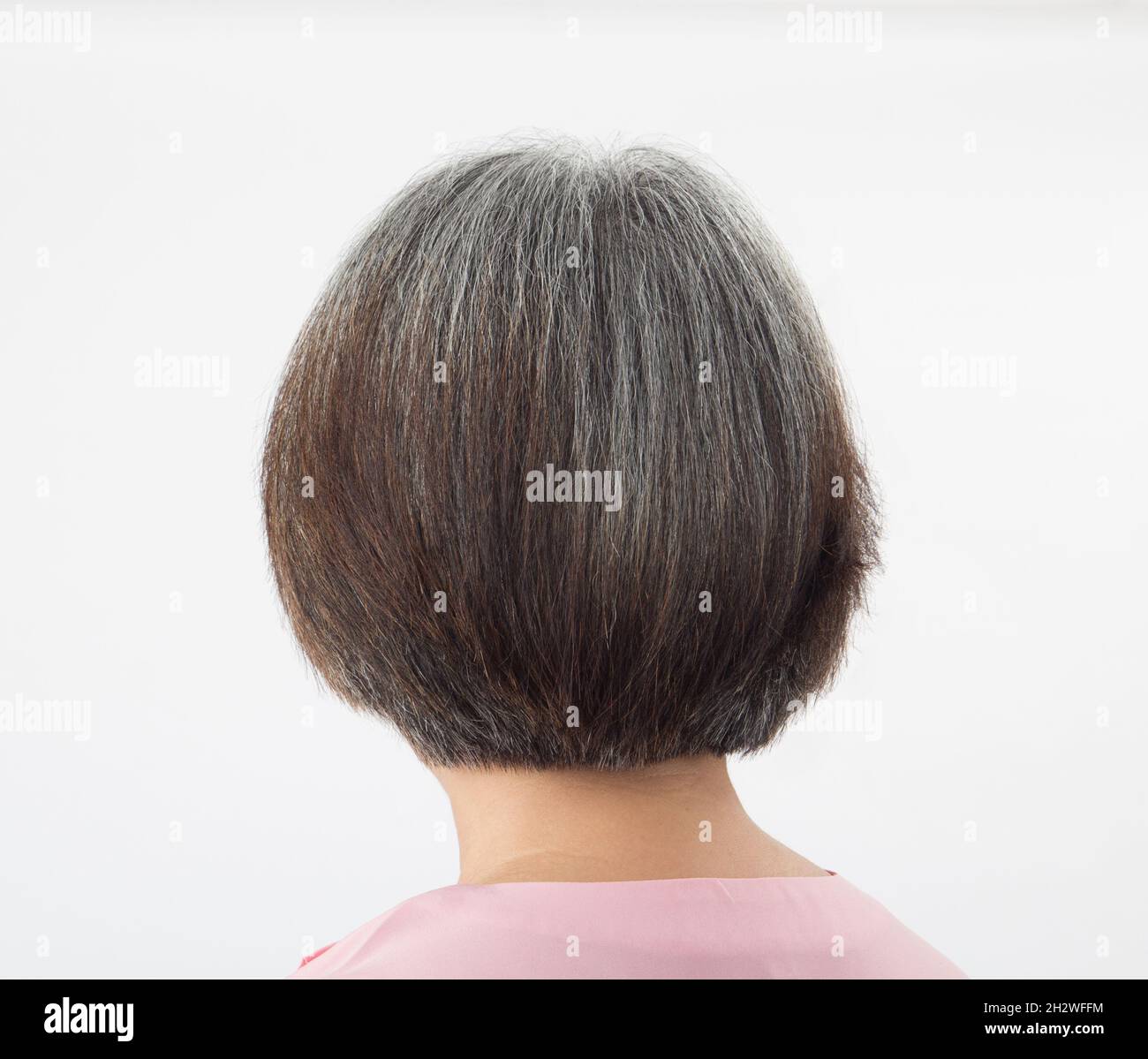 Testa di donna anziana trasformante a capelli grigi, da dietro su sfondo bianco Foto Stock