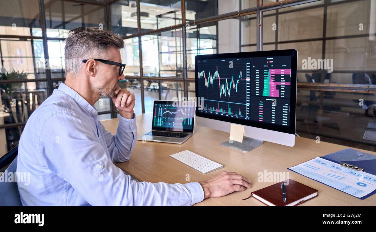 Trafficato Crypto trader utilizzando il computer che analizza il grafico digitale di trading del mercato azionario. Foto Stock