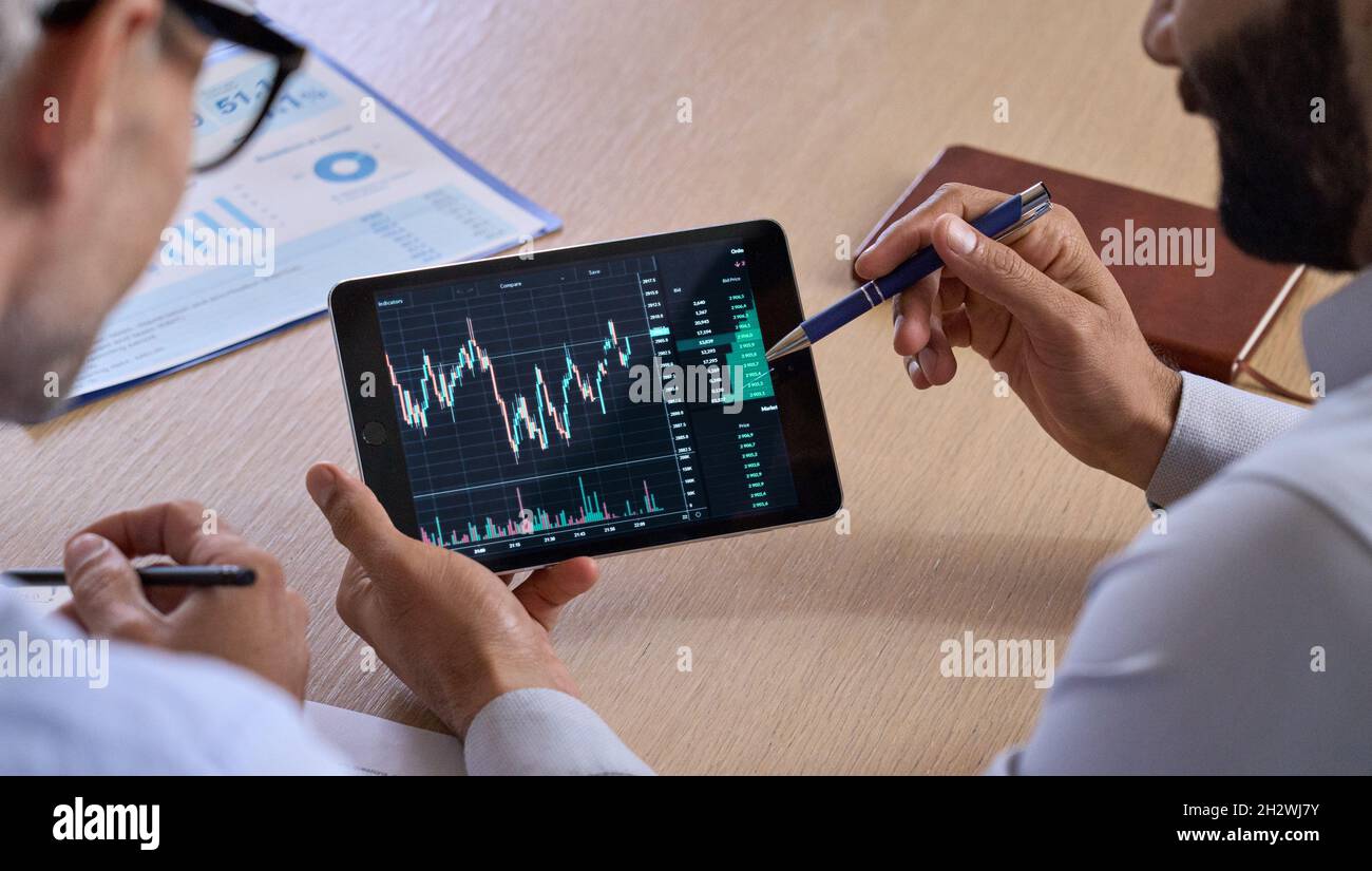 Investitore che si occupa di consulenza per il trader che mostra la tabella di scambio criptato utilizzando un tablet digitale. Foto Stock