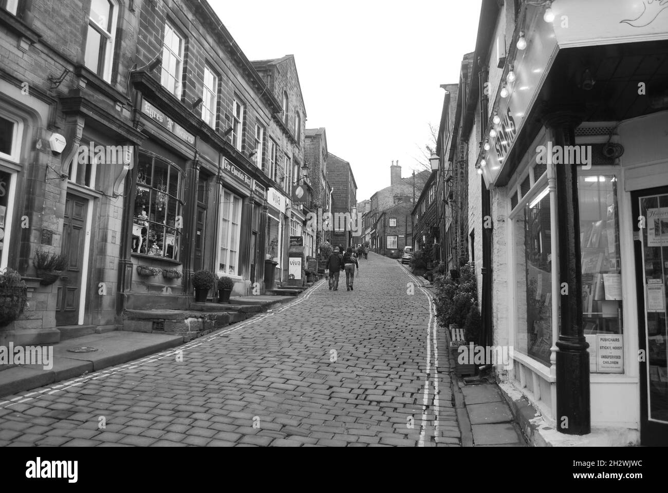 Strada principale ripida del villaggio storico di Haworth nel West Yorkshire Foto Stock