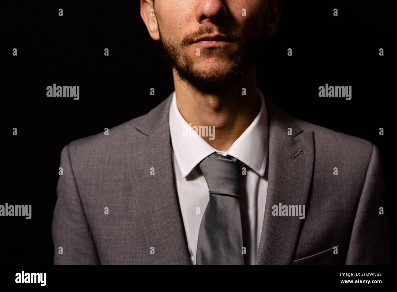 Un uomo d'affari sconosciuto che indossa un abito grigio intelligente, immagine ravvicinata che mostra la metà inferiore del viso e delle spalle Foto Stock