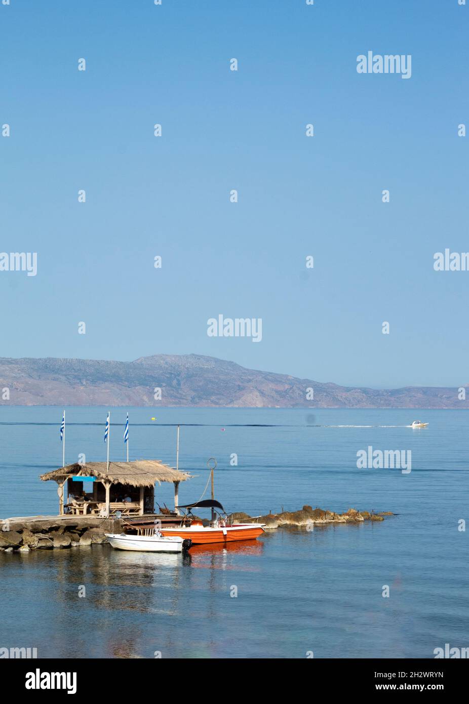Agia Marina resort, Chania, Creta, Grecia piccole barche ormeggiate in uno scenario tranquillo e grazioso molo con spazio copia nel cielo blu foto verticale Foto Stock