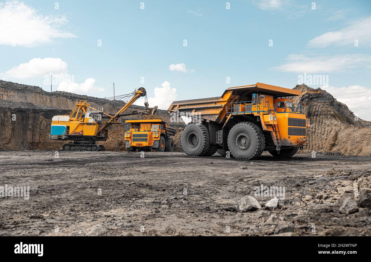 Dumper da cava di grandi dimensioni. Grande dumper da miniera giallo sul luogo di lavoro. Caricamento del carbone nel camion della carrozzeria. Produzione di minerali utili. Macchinari per attività estrattive di autocarri Foto Stock