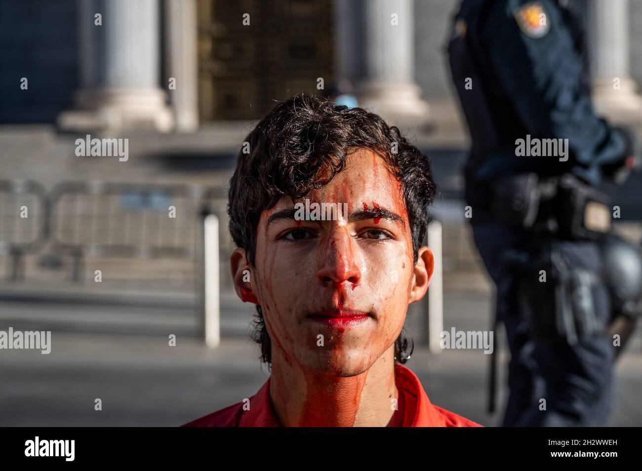 Madrid, Spagna. 24 ottobre 2021. Un attivista del gruppo di protesta contro il cambiamento climatico della ribellione di estinzione di fronte al Parlamento spagnolo coperto di sangue falso chiedendo azioni per combattere il cambiamento climatico. Credit: Marcos del Maio/Alamy Live News Foto Stock