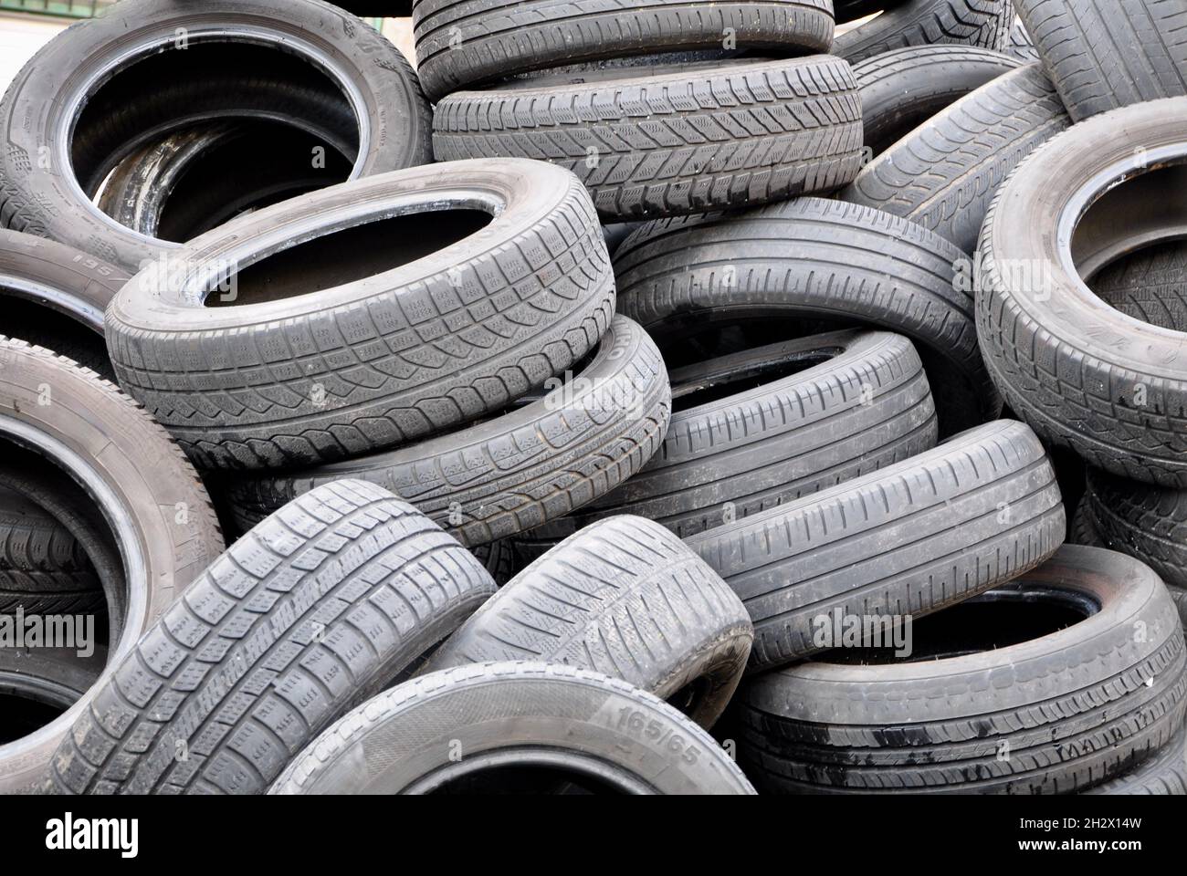 Vecchio sfondo di riciclaggio dei pneumatici. Texture dei rifiuti degli pneumatici. Un mucchio di vecchi pneumatici di protezione auto usati al servizio auto o scarico con rifiuti e rifiuti pronti Foto Stock