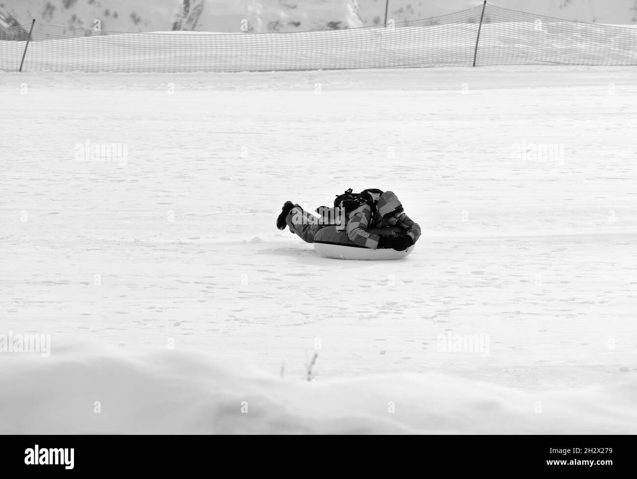 Tubing sulla stazione sciistica in giornata di sole in montagne innevate. Vacanza invernale. Immagine in bianco e nero. Foto Stock