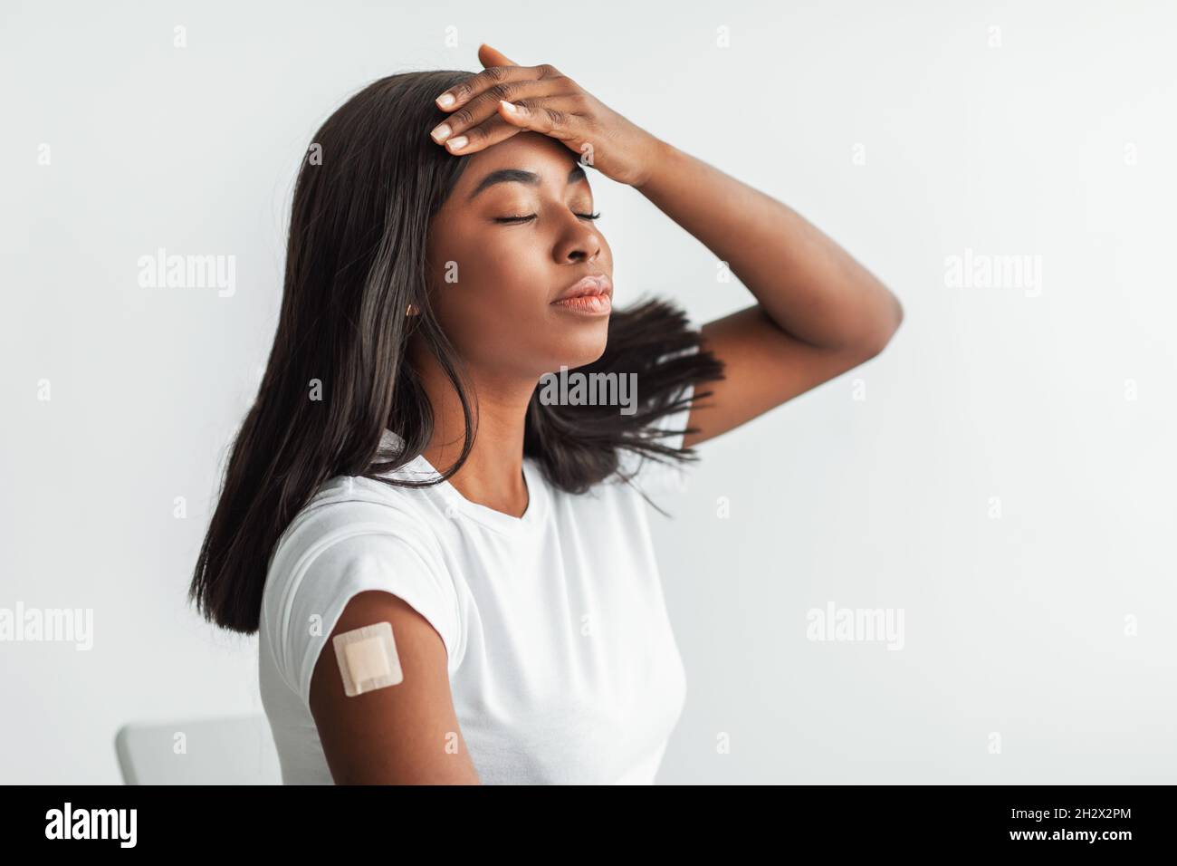 Effetti indesiderati del vaccino. Donna con bendaggio adesivo che soffre di febbre Foto Stock