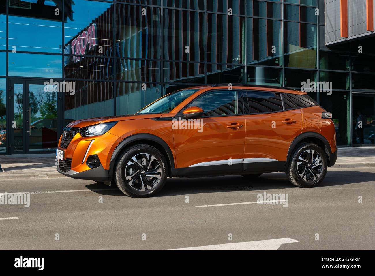 Kiev, Ucraina - 12 giugno 2021: Fotografia di Peugeot 2008 arancione di fronte al moderno centro business Foto Stock