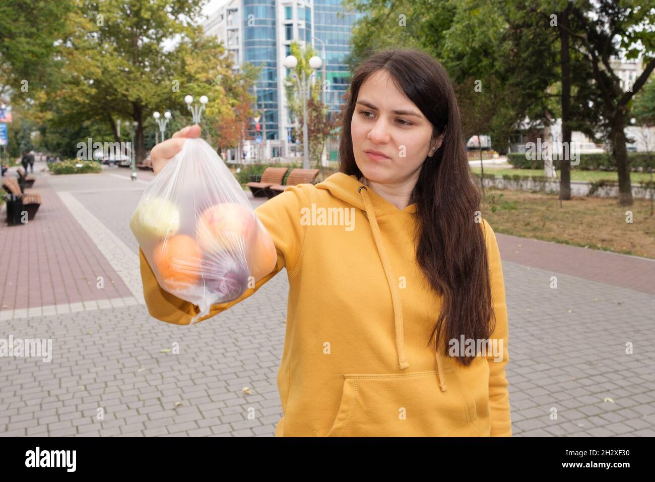 Una donna brunetta tiene un sacchetto di plastica di frutta nel parco. Foto Stock