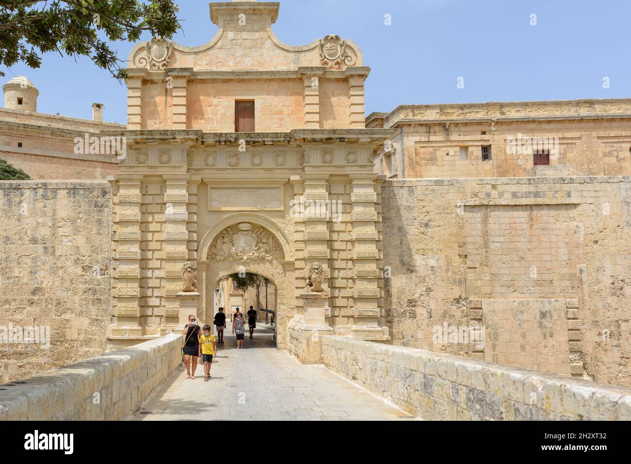 I turisti camminano attraverso il portale barocco della porta Mdina, conosciuta anche come la , che è la porta principale della città fortificata Foto Stock