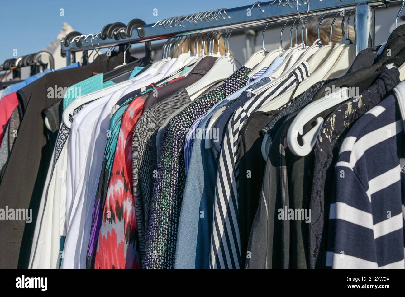 Usato abiti di seconda mano su appendiabiti su un portabiti, come donazione a un ente di beneficenza o per la vendita di mercato delle pulci, fuoco selezionato, profondità di campo stretta Foto Stock