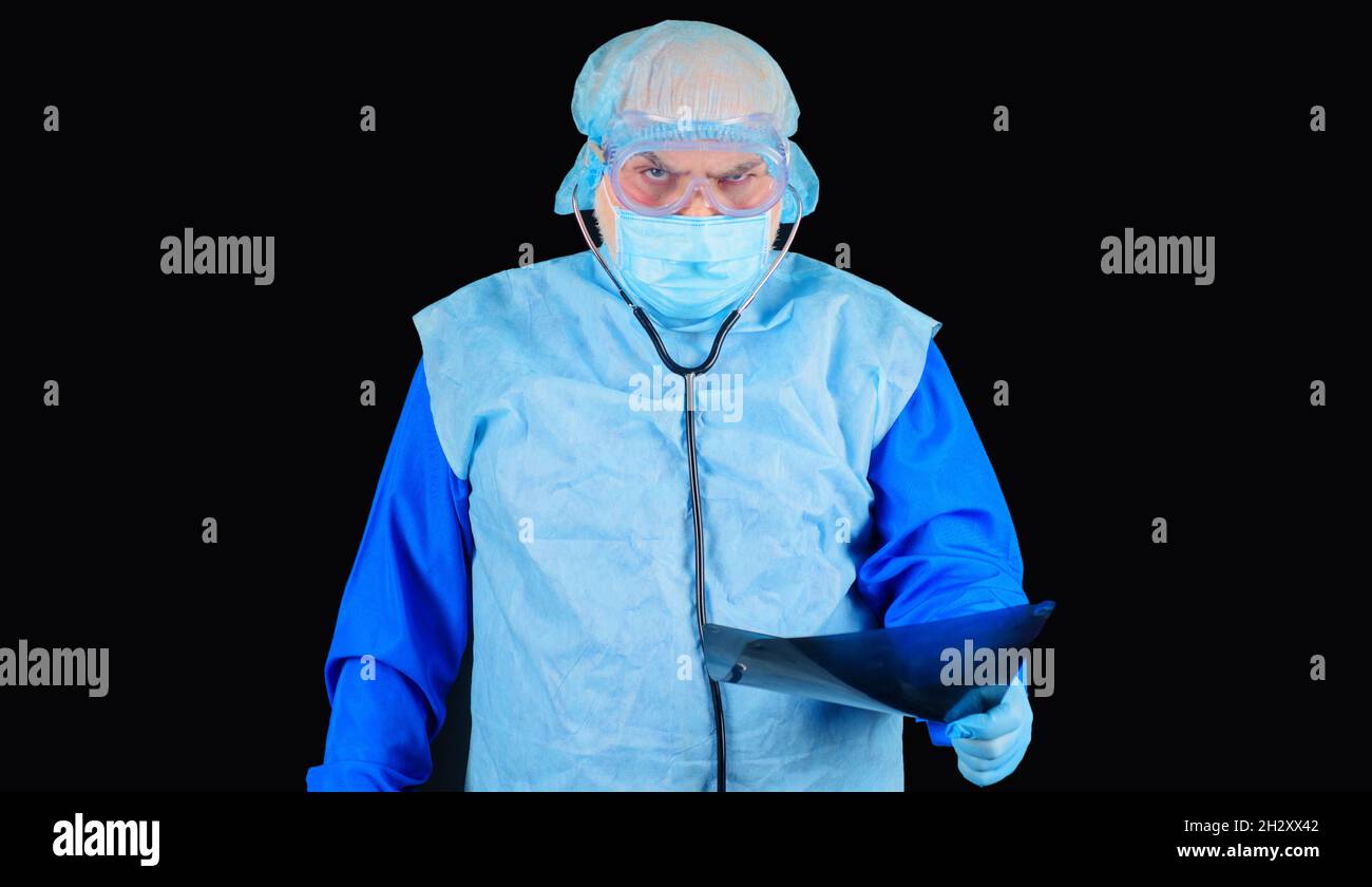 Medico di sesso maschile in tuta protettiva e maschera medica guardando i raggi X. Radiologo con raggi X del paziente. Medico che esamina la radiografia polmonare Foto Stock